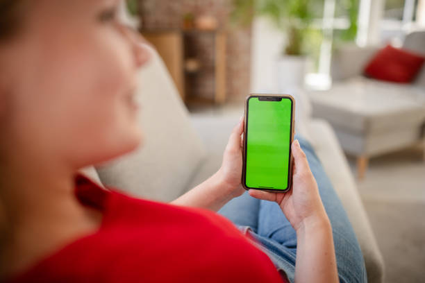 istock Person holding smartphone with green screen on couch 2169887651