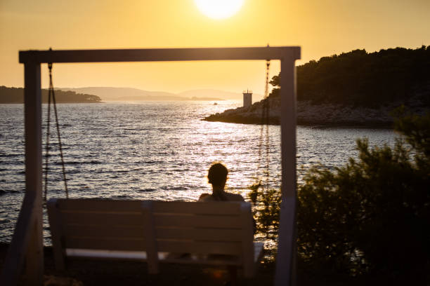 Unrecognizable woman is watching sunset near by Adriatic Sea.\nHvar - Croatia.