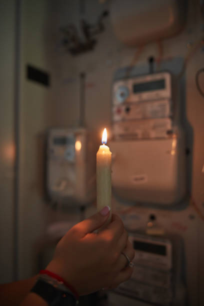 istock Checking the electricity power meter with a candle in cold winter days while there is power outage. 2169893565