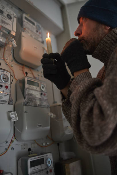 istock Checking the electricity power meter with a candle in cold winter days while there is power outage. 2169893617