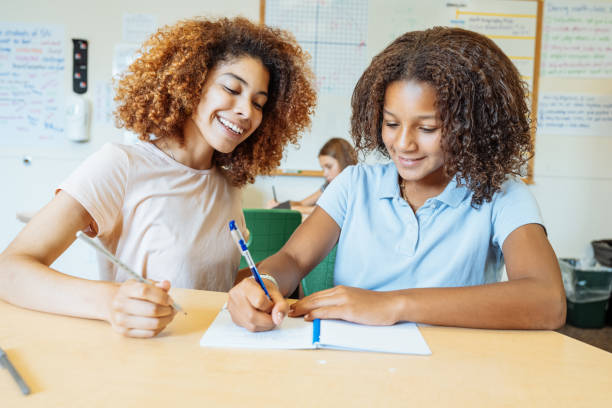 istock Young teacher helping a young multiracial student with her writing assignment in a classroom setting, fostering education and learning. 2169899772