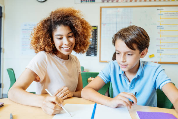 istock A millennial Latina teacher helping a young student with his writing assignment in a classroom setting, fostering education and learning. 2169899850