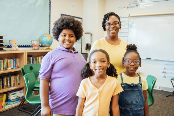 istock A cheerful black teacher standing with three happy elementary students in a bright and colorful classroom environment. 2169899973