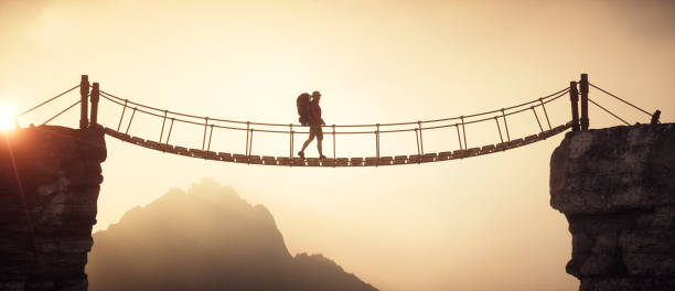 istock Hiker walking on a suspension bridge between mountains. 2169902865