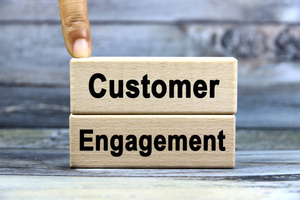 istock Customer engagement wording or text on wood block with hand on grey background.Copy space and business concept. 2169903254