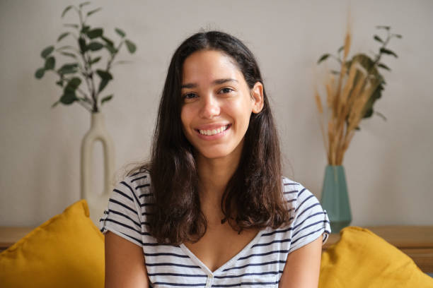 istock Young latin woman is smiling while sitting on the couch at home 2169908507
