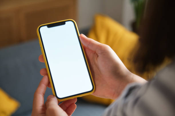 Woman holding a smartphone with a white screen, perfect for mockups and showcasing mobile apps or websites