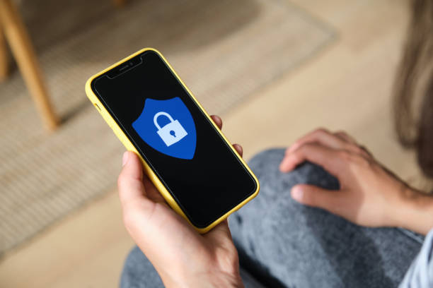 istock Woman holding smartphone with security shield on screen at home 2169909771