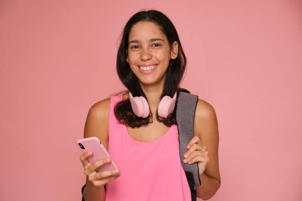 istock Happy latin student girl using smartphone on pink background 2169912437