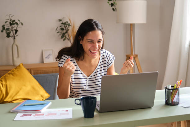 istock Excited young woman celebrating success while working at home office 2169912827
