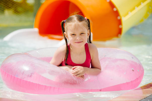 Child in Swimsuit on Inflatable Ring, Smiling and Looking into Camera