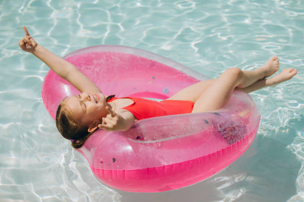 istock Little Girl Relaxing on Inflatable Ring in Pool 2169915604