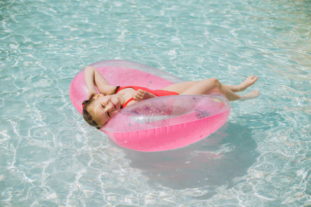 istock Little Girl Relaxing on Inflatable Ring in Pool 2169915825