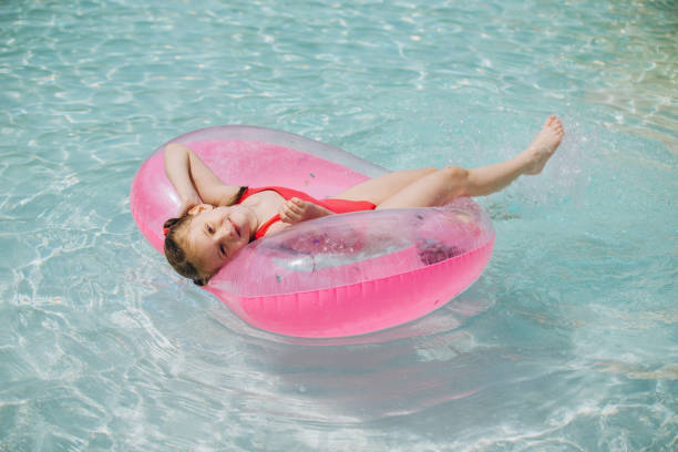 istock Smiling Girl on Inflatable Ring in Swimming Pool, Looking at Camera 2169915892