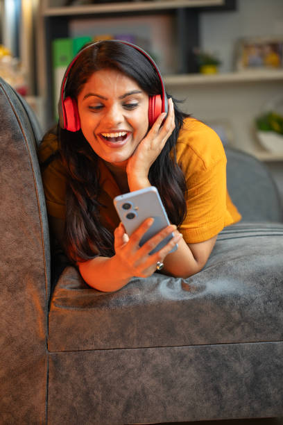 istock Happy young woman using smart phone on sofa at home 2169917893
