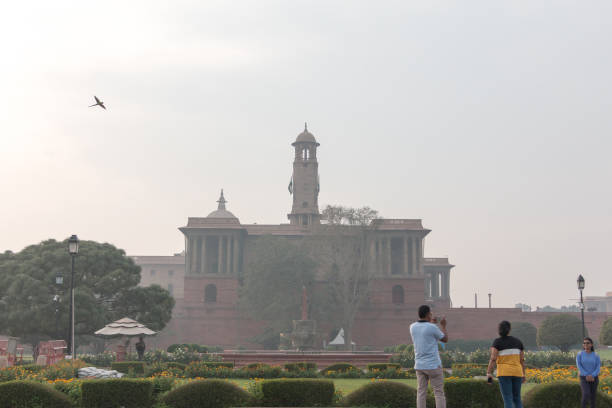 New Delhi, India - Feb19, 2023: The Indian parliament in New Delhi is considered one of the finest government buildings. The building was built in 1919 and designed by architect Edwyn Lutyens, and, like all government buildings in the country, it is well maintained and surrounded by beautiful gardens with a lake. The Parliament of India, also called the Sansad, is the highest legislative body in the country. The word Sansad in Sanskrit language means home. It is in New Delhi, next to the president's home, the Rashtrapati Bhawan Palace.\nAs it was not possible to visit, I only have this photo from afar.
