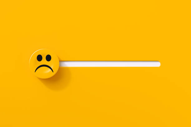 Sad face over slider button on yellow background. Horizontal composition.