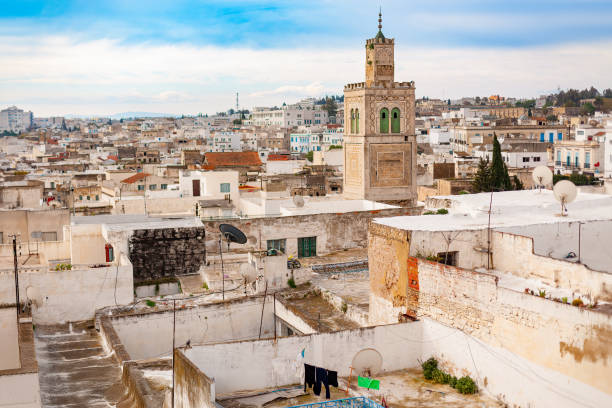 Tunis reveals its rich history through a blend of architectural styles, with rooftops adorned with clothes drying in the sun and a prominent minaret dominating the skyline.
