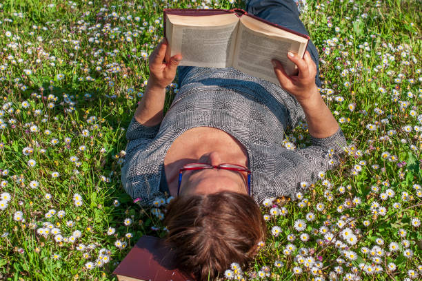 Lady lying in the grass reading a book