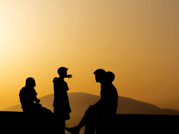 Boys silhouettes in dramatic gold coloured sunset, Hydra island, Greece