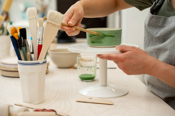 istock Using a brush to paint a ceramics bowl. Learning how to paint a handmade pottery project. Girl is decorating a clay product with bright green color. 2169934268