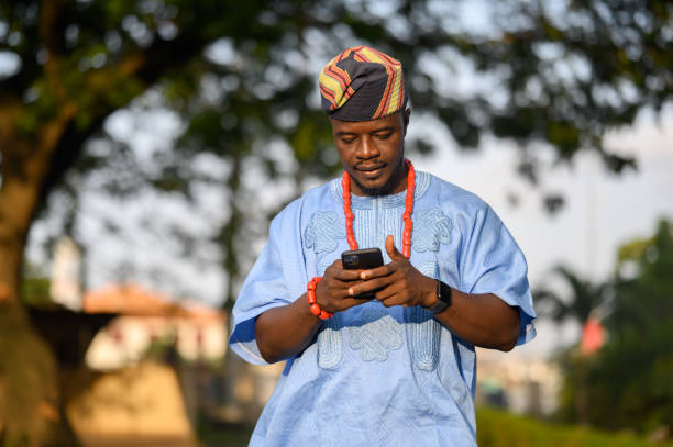 istock Yoruba man in blue native attire joyfully replying on smartphone. 2169937145