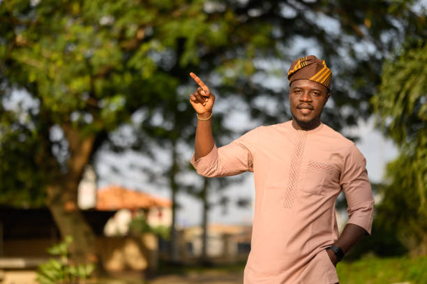 istock Smiling Nigerian man gesturing towards ad copy space with friendly demeanor. 2169937719