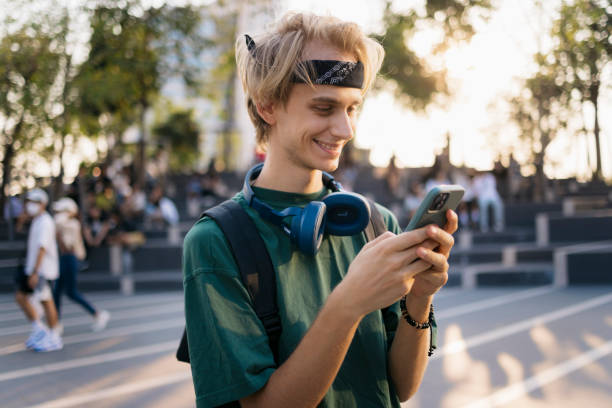 istock Carefree male student using mobile phone standing in university campus 2169942003