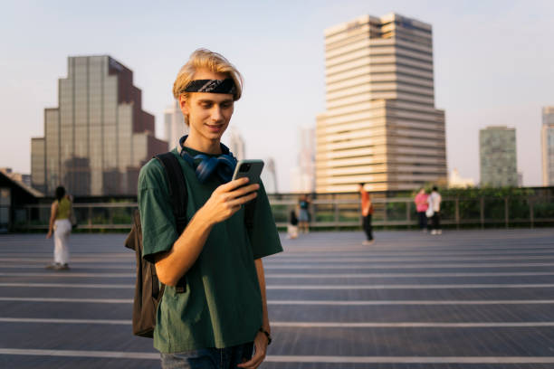 istock Male student using cell phone walking outside in the city 2169942154