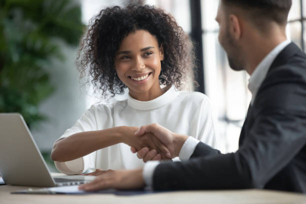 istock Happy loan manager shaking hands with client in modern office 2169942971