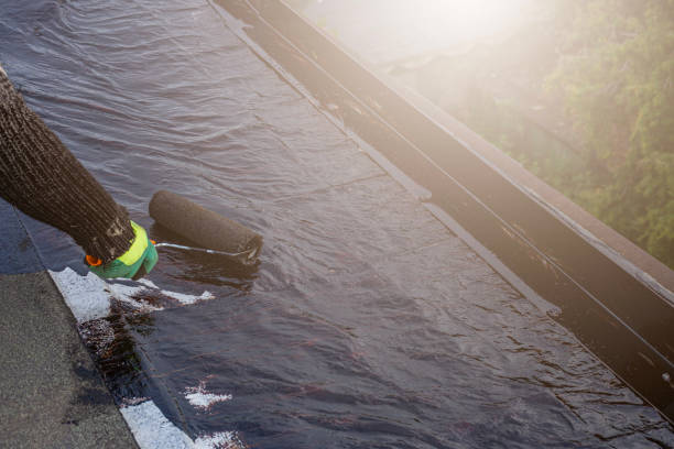 a young worker treats a roof with bitumen primer before applying rolled asphalt roofing using a torch