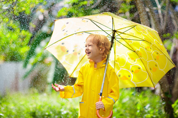istock Child playing in the rain. Kid with umbrella. 2169944460