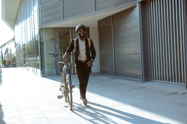 istock Businessman walking with bicycle on sunny urban sidewalk 2169944882