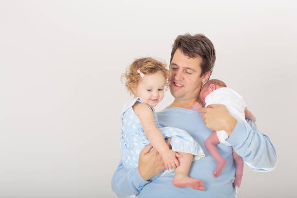 Father holding newborn baby boy. New born child sleeping under a blue knitted blanket. Children sleep. Dad holding infant. Healthy little kid shortly after birth.