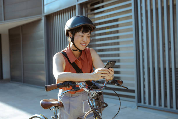 istock Woman on bicycle using smartphone outdoors in urban setting 2169945967