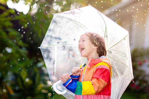 Child playing in autumn rain. Kid with umbrella.