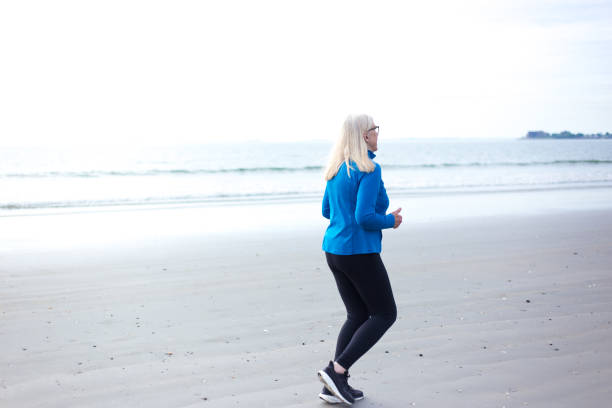istock Active Senior Woman Jogging on Beach 2169946418