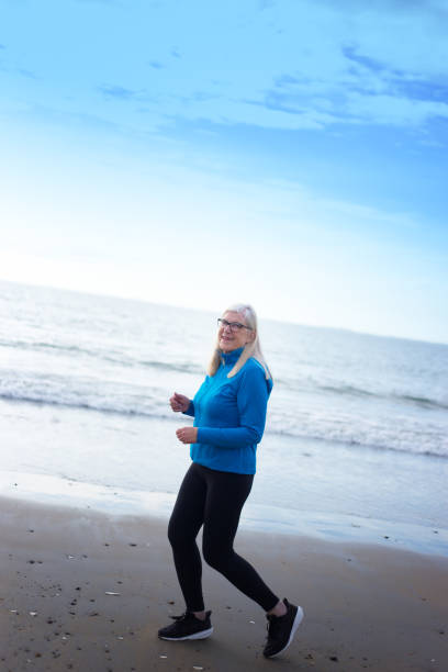 istock Smiling Active Senior Woman Jogging on Beach, Looking at Camera 2169948438
