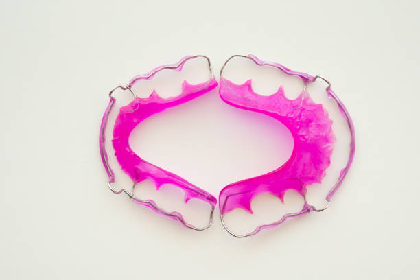 Pink acrylic dental retainer on white background