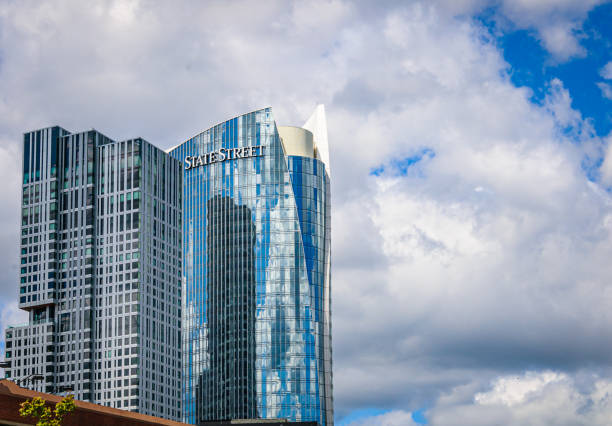 Boston, Massachusetts, USA -August 12, 2024- The modernistic glass facade of the State Street Bank building reflects the sky and clouds on an August morning.