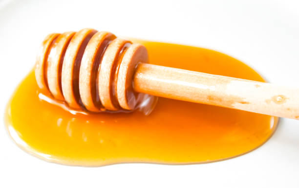 istock honey dripping from a dipper, isolated on white background 2169957753