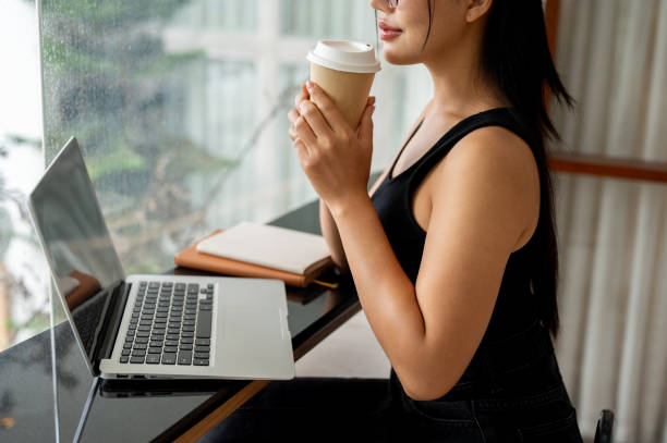 istock A woman enjoying coffee while working remotely from a modern, minimalist coffee shop. 2169960346