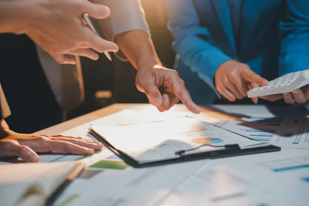 istock Business professionals collaborate in an office, working on documents and analyzing charts, discussing, brainstorming, and problem solving for success and growth 2169965605