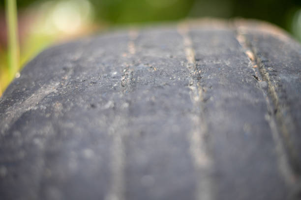 A close up of a tire with a black stripe. The tire is old and worn, with a few cracks and scratches