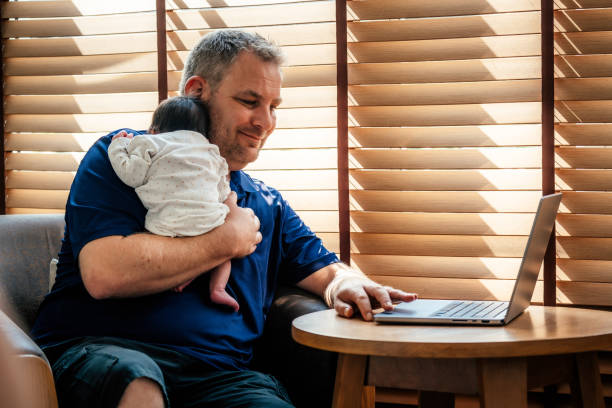 Father using laptop with newborn baby girl