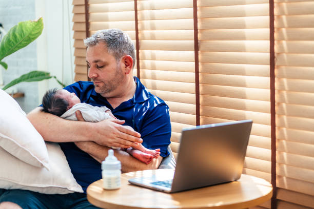 istock Father holding baby girl and using laptop 2169969925