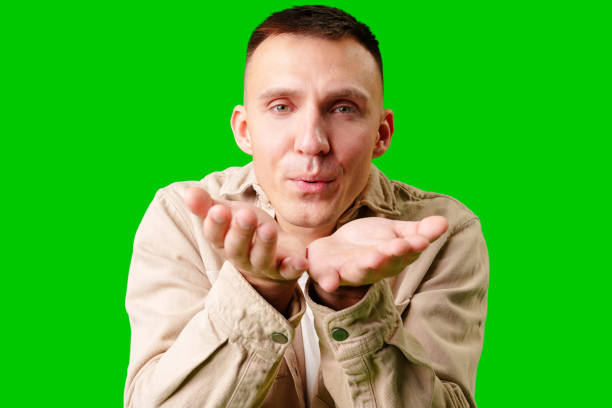 istock Young Man Making Playful Gesture With Open Hands Against Bright Green Background 2169974374