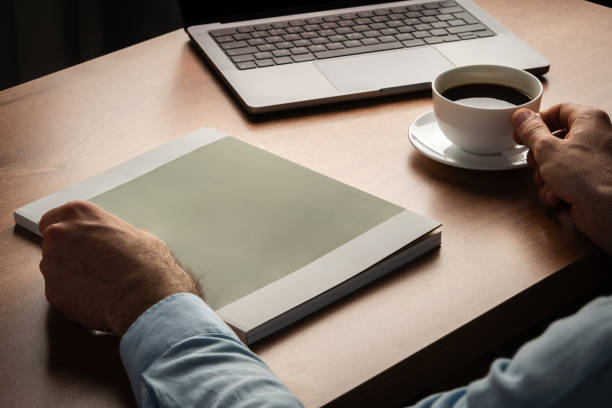 istock Man Reading Page of Magazine While Holding Coffee Cup 2169974585