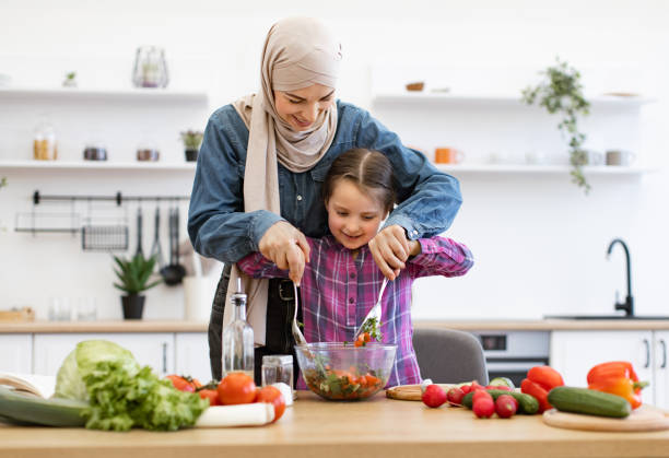 istock Muslim mother and daughter preparing fresh vegetable salad in kitchen 2169975018