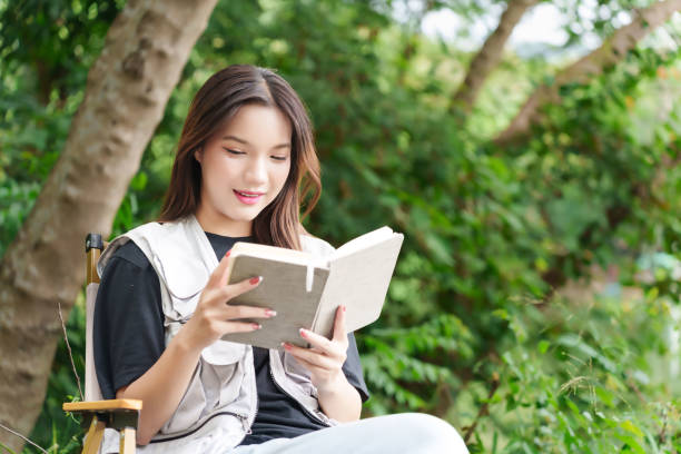 istock A hiker sitting in the forest, reading a book. She is surrounded by lush greenery, enjoying a peaceful moment in nature 2169978024